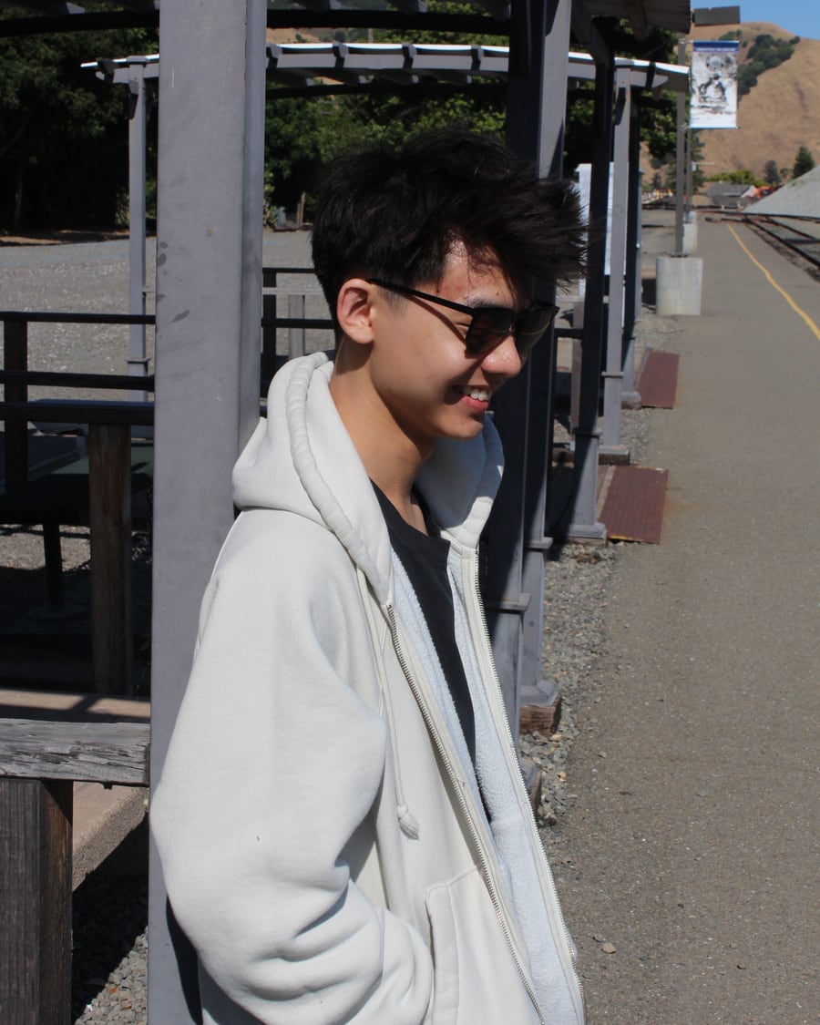 Carson smiling beside the tracks at an outdoor train station