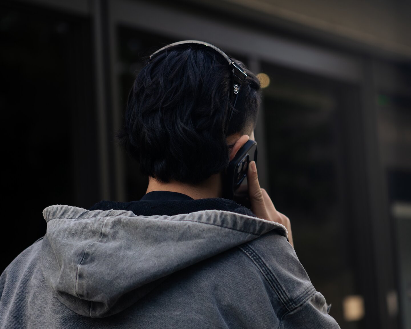 A person seen from behind speaking on a phone in a transit space