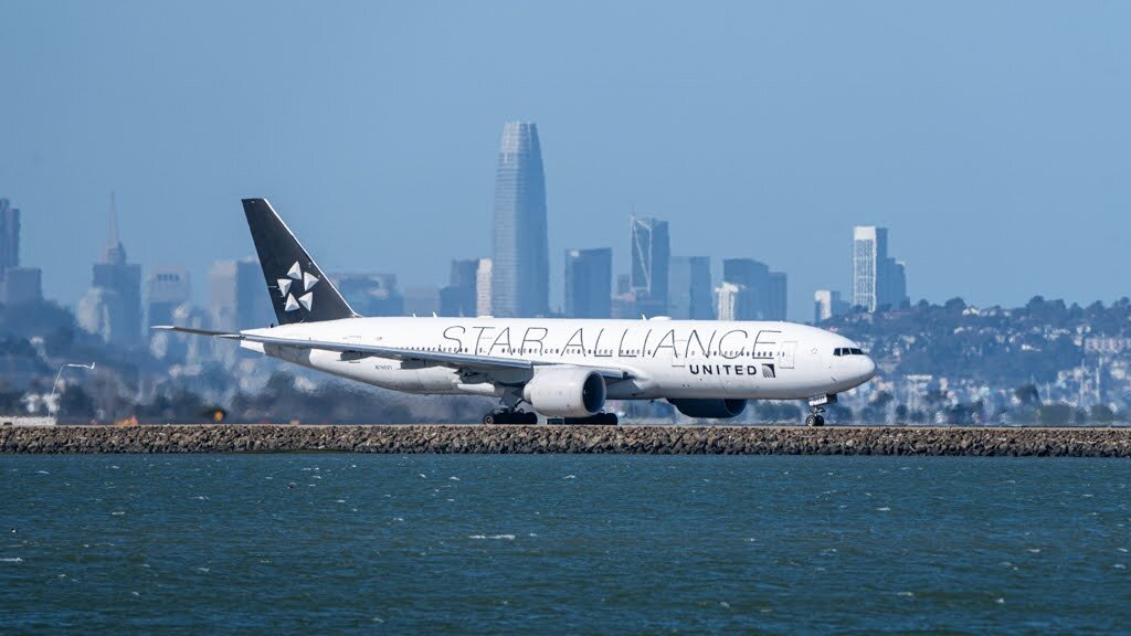 A Star Alliance aircraft moving beside blue water with the San Francisco skyline behind it