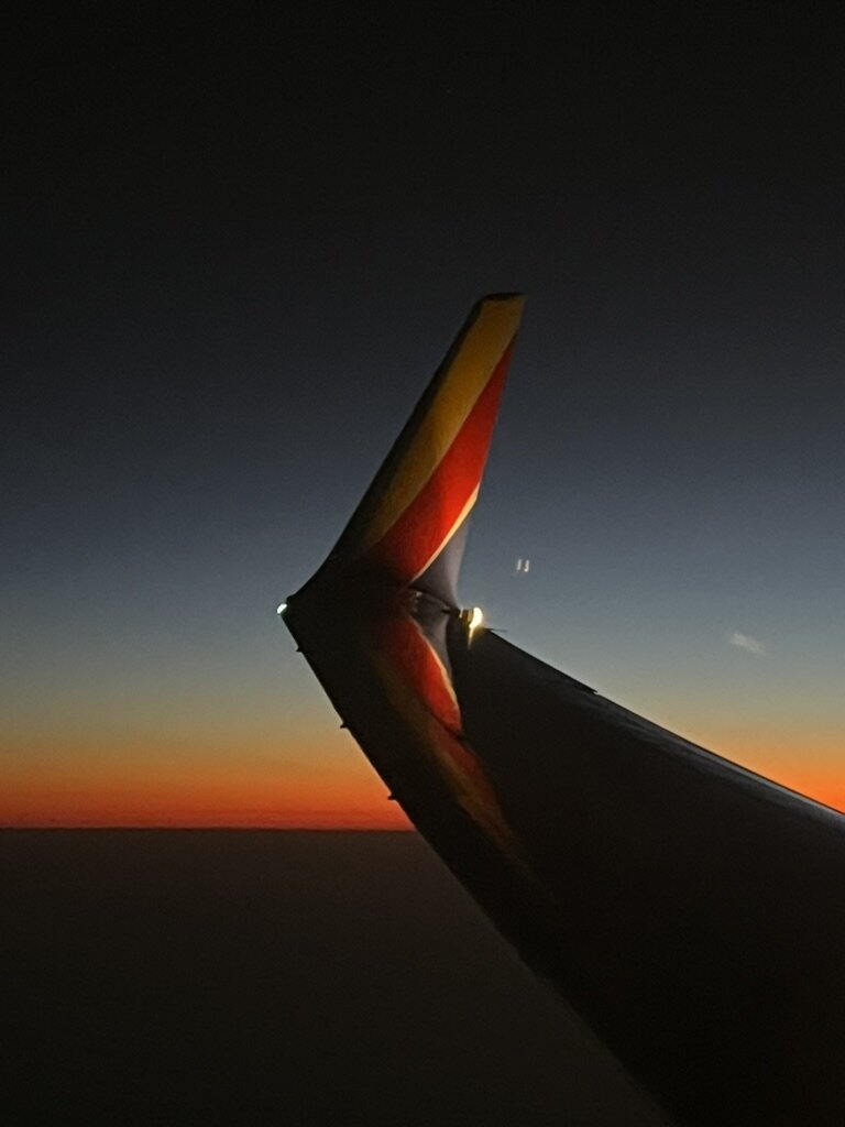 An aircraft winglet silhouetted against a dark blue and orange dusk sky